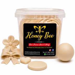 A clear plastic tub of Honey Bee confectionery product with a black label, shown with several beige decorative pieces including a flower, bow, heart, oval, and round disc on a white background.