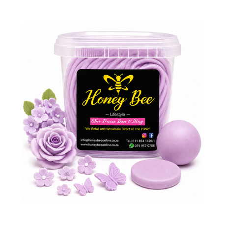 A clear plastic tub filled with lavender-colored wax melts, shown with a black front label reading Honey Bee Lifestyle. Surrounding the tub are lavender wax flower and butterfly ornaments, a lavender wax ball, and a round lavender wax disc, all on a white background.