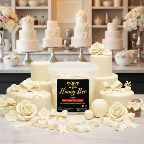 A jar of Honey Bee Luxury Flower Paste & Glitter displayed on a marble countertop with decorated cream-colored cakes and fondant roses in the background.