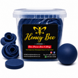 A clear plastic tub filled with dark blue round bath bombs, with three rose-shaped bath bombs and a flat round bath bomb displayed on either side. The front of the tub features a black label with a yellow bee logo and the brand name 'Honey Bee Lifestyle'.