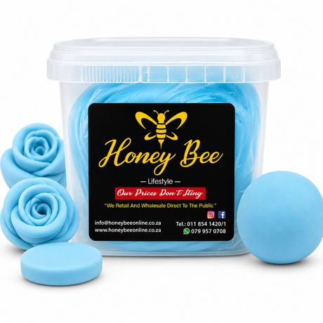 A clear plastic tub filled with light blue fondant, shown on a white background with several loose blue fondant arranged around it. The front of the tub has a black label with a yellow bee logo and the brand name 'Honey Bee Lifestyle'.