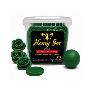 A clear plastic tub of Honey Bee lip balm or wax melts filled with dark green discs, shown on a white background with several loose green balm pieces arranged around it. The front label reads Honey Bee with a yellow bee logo.
