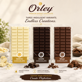 Three bars of Orley premium baking chocolate in white, dark, and milk chocolate flavors, displayed side-by-side with decorative chocolate pieces and cream on a light marble surface.